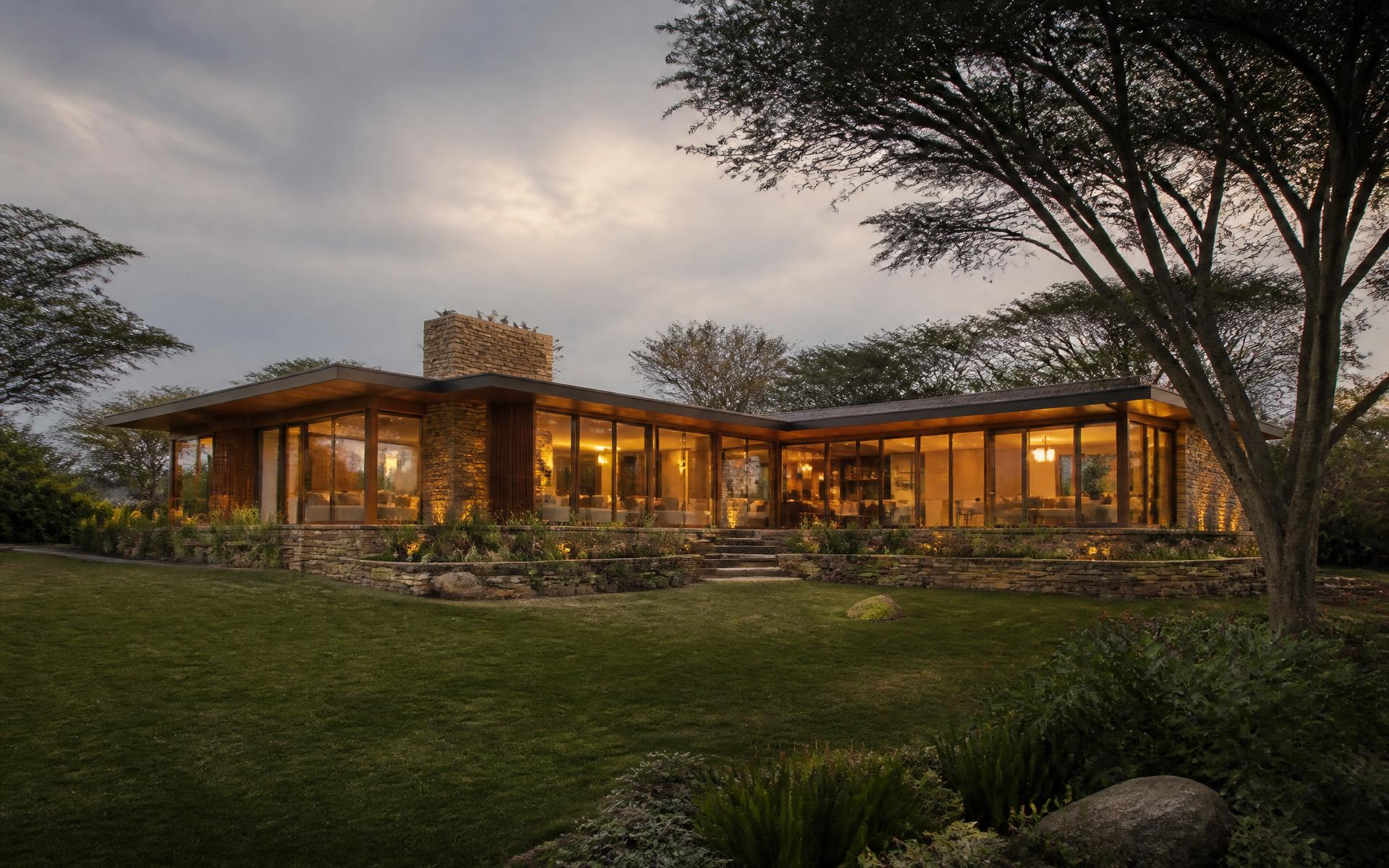 Contemporary Kenyan home at dusk with lit interiors and a mature garden